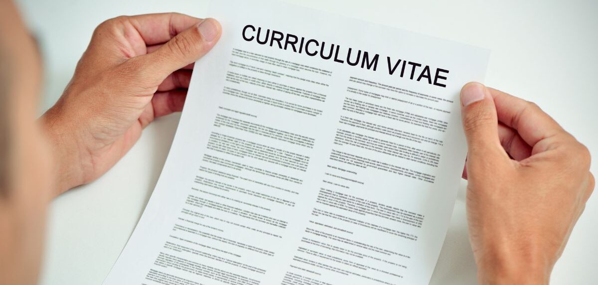 Student writing an internship cover letter at a desk with laptop and notebook