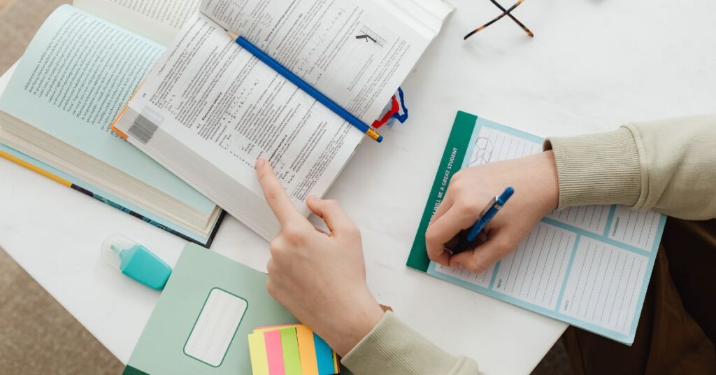 Student creating an outline for an academic essay with notes and a laptop